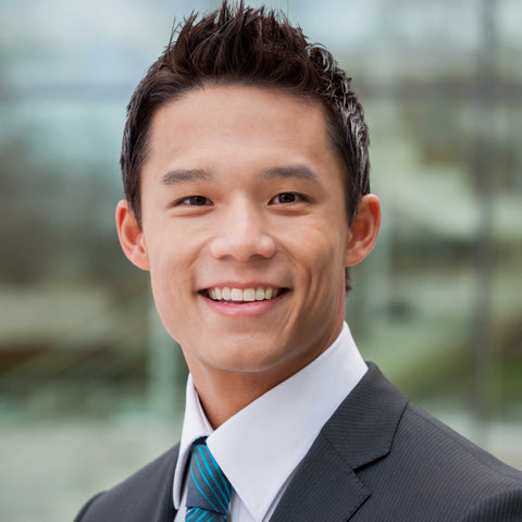 A man in a suit, smiling and showing smooth hair-free face and neck results from laser hair removal.